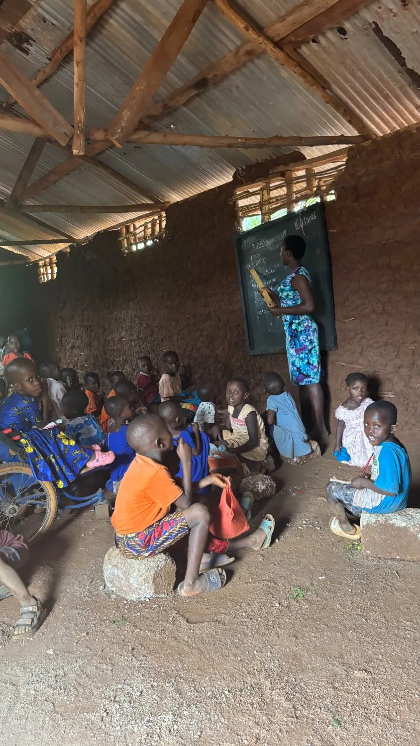 Children learn inside a simple classroom with mud walls and a corrugated iron roof, in a rural community in Kilifi County, Kenya.